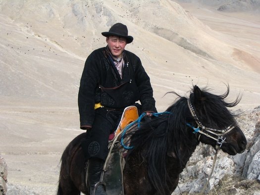Young man in traditional Mongolian clothes on horse